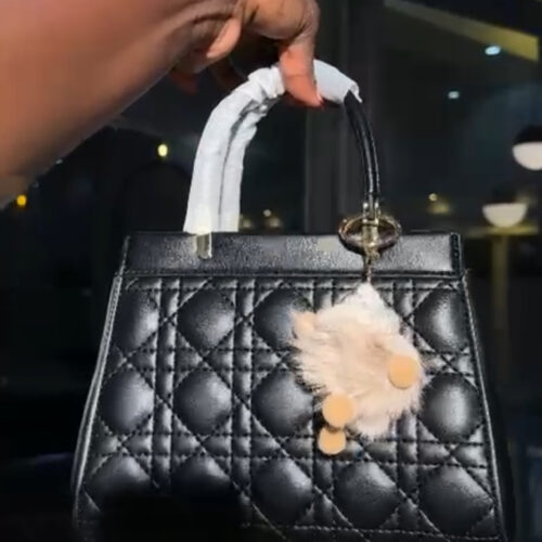 Christian Dior Lady Dior bag in black lambskin with Cannage stitching and gold-finish metal D.I.O.R. charms.